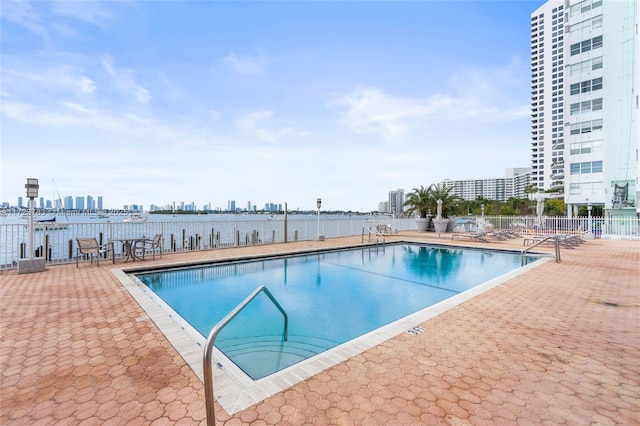 view of swimming pool with a patio area and a water view