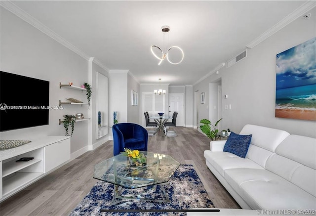 living room featuring light hardwood / wood-style flooring, crown molding, and an inviting chandelier