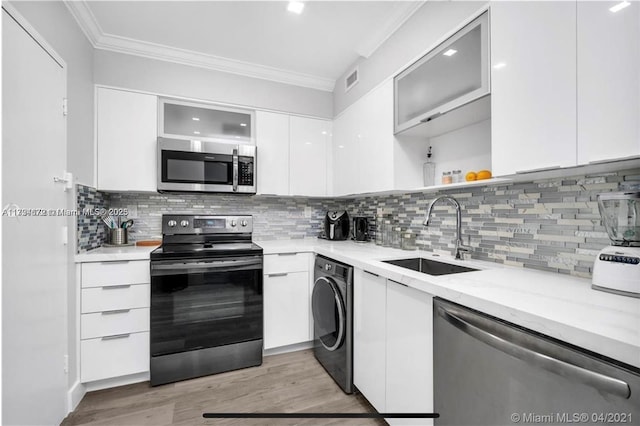 kitchen with white cabinetry, sink, backsplash, washer / dryer, and appliances with stainless steel finishes