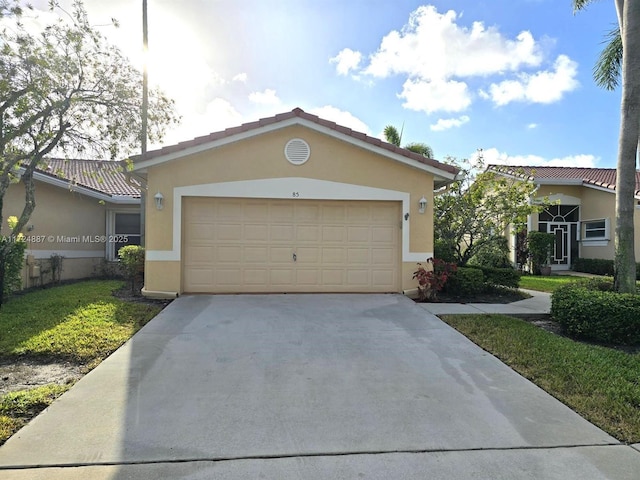 view of front of house with stucco siding, driveway, a tile roof, and a garage