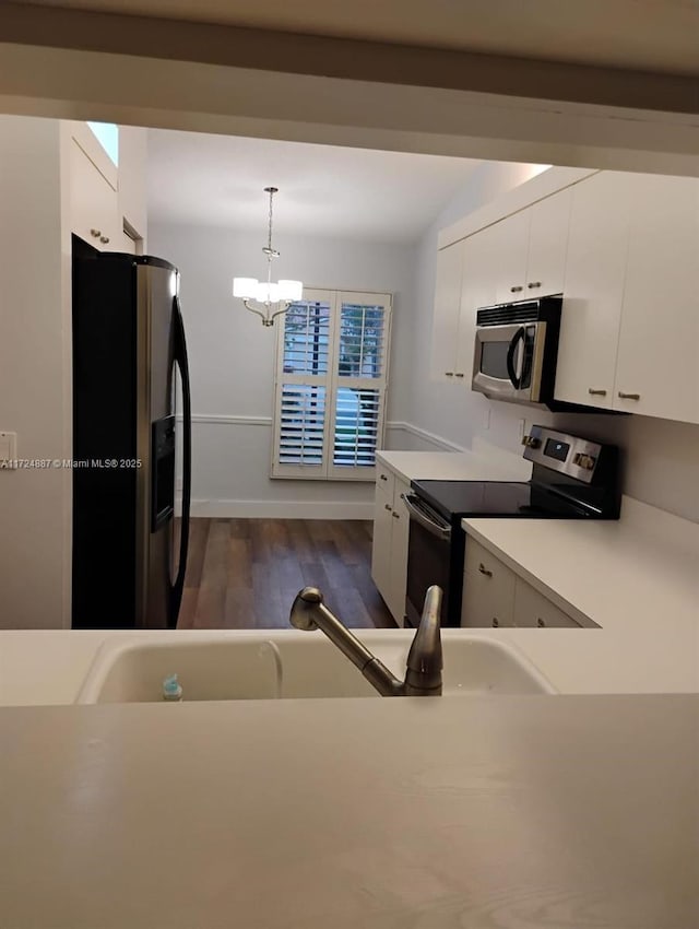 kitchen with pendant lighting, light countertops, stainless steel appliances, dark wood-style floors, and white cabinetry