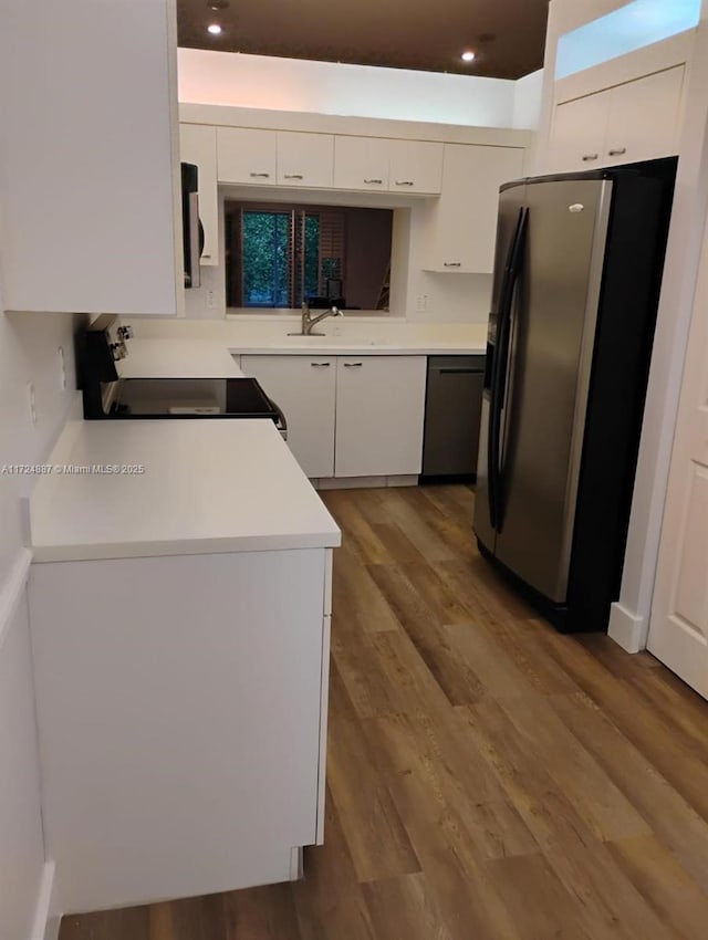 kitchen with black appliances, white cabinets, wood finished floors, and light countertops