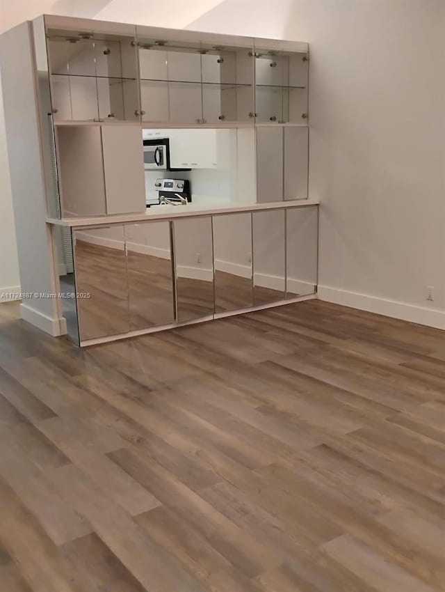 kitchen with appliances with stainless steel finishes, baseboards, and wood finished floors