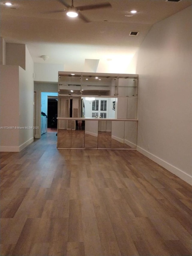 interior space with visible vents, a ceiling fan, baseboards, and wood finished floors