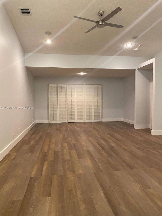 finished basement featuring a ceiling fan, dark wood-style flooring, and baseboards