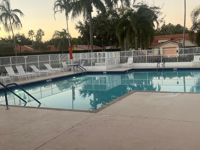 pool at dusk featuring a patio area, a community pool, and fence