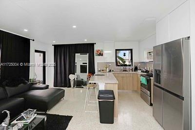 kitchen with appliances with stainless steel finishes, a center island, white cabinetry, and light brown cabinetry