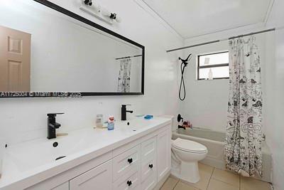 full bathroom with tile patterned flooring, vanity, shower / tub combo, and toilet