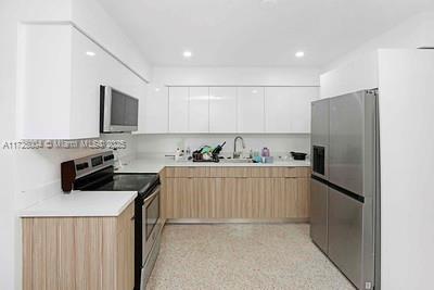 kitchen with white cabinetry, sink, light brown cabinets, and appliances with stainless steel finishes