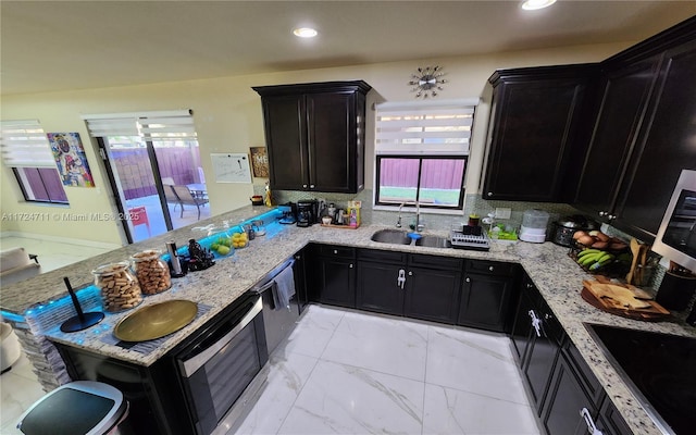 kitchen with kitchen peninsula, light stone countertops, and sink