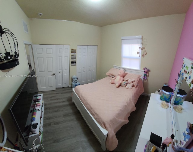 bedroom with dark hardwood / wood-style floors and multiple closets