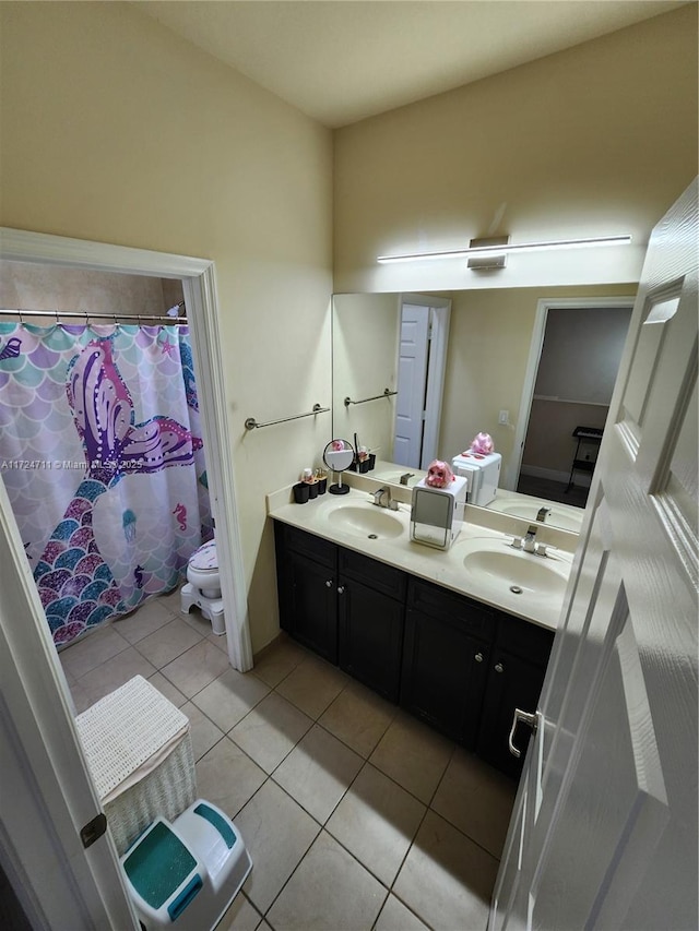 bathroom with toilet, vanity, and tile patterned floors