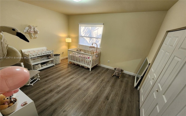 bedroom with a closet, dark wood-type flooring, and a crib