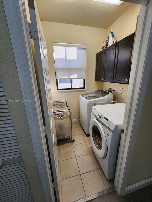 laundry room featuring cabinets, light tile patterned floors, and washing machine and dryer