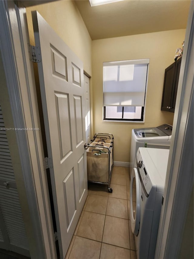 washroom featuring light tile patterned flooring, cabinets, and washing machine and dryer