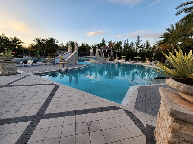 pool at dusk with a patio area