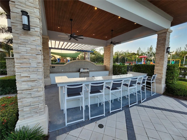 view of patio / terrace with area for grilling, ceiling fan, an outdoor bar, and exterior kitchen