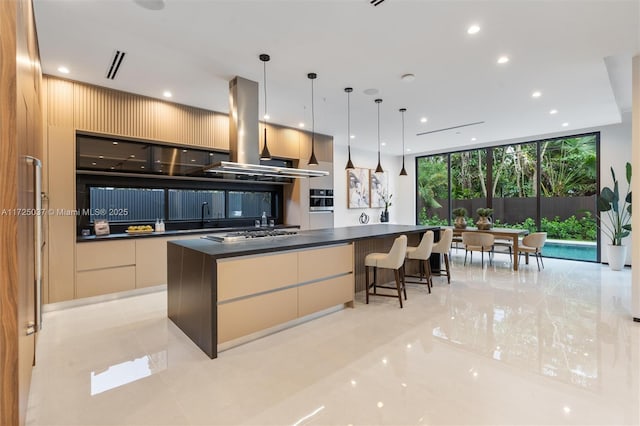 kitchen featuring island exhaust hood, stainless steel gas stovetop, light tile patterned floors, a center island, and hanging light fixtures