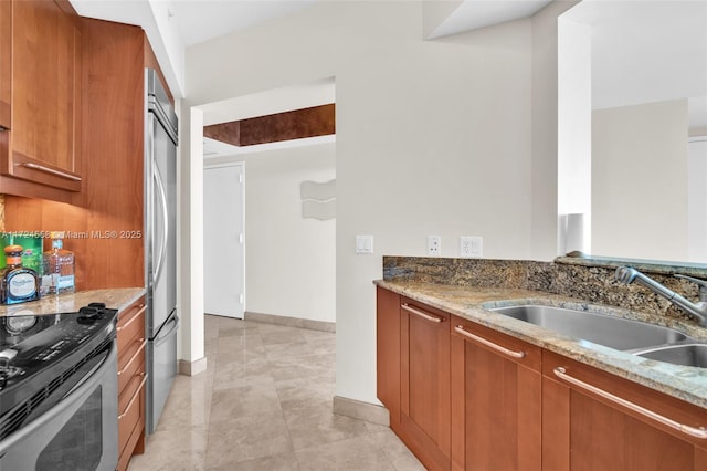 kitchen featuring light stone countertops, stainless steel appliances, and sink