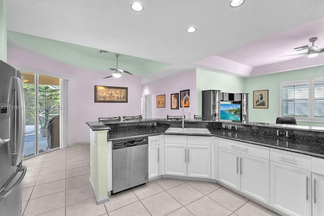 kitchen featuring white cabinetry, stainless steel appliances, light tile patterned floors, and dark stone counters