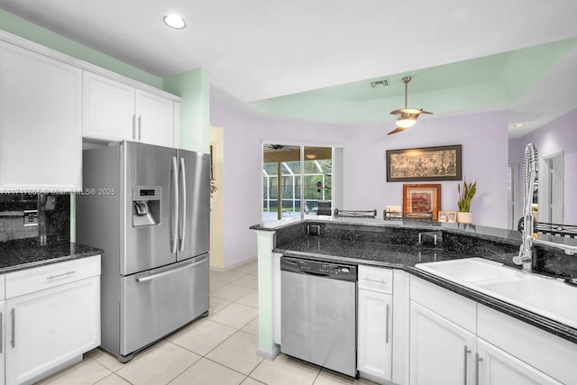 kitchen with sink, dark stone countertops, white cabinets, light tile patterned floors, and stainless steel appliances