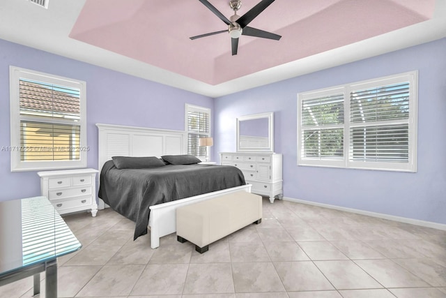 tiled bedroom with a raised ceiling and ceiling fan