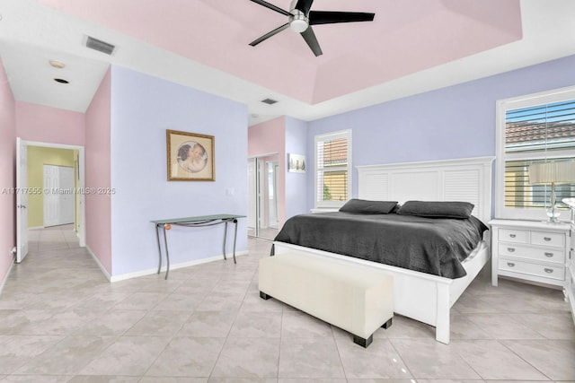 tiled bedroom with a raised ceiling and ceiling fan