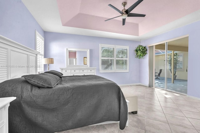 tiled bedroom featuring ceiling fan, a raised ceiling, multiple windows, and access to outside