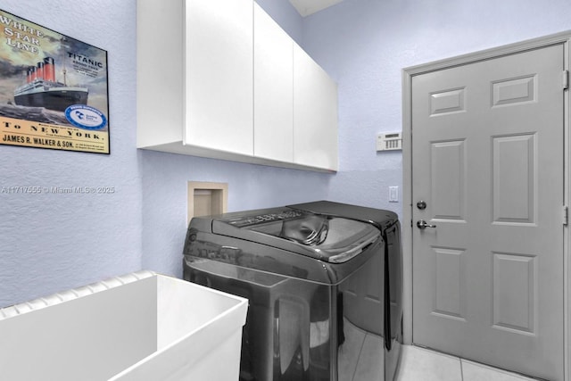 clothes washing area with cabinets, sink, washing machine and dryer, and light tile patterned floors