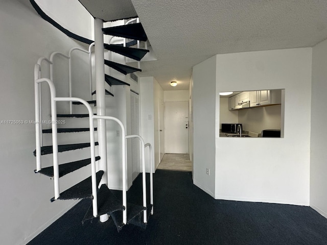 stairway featuring carpet and a textured ceiling