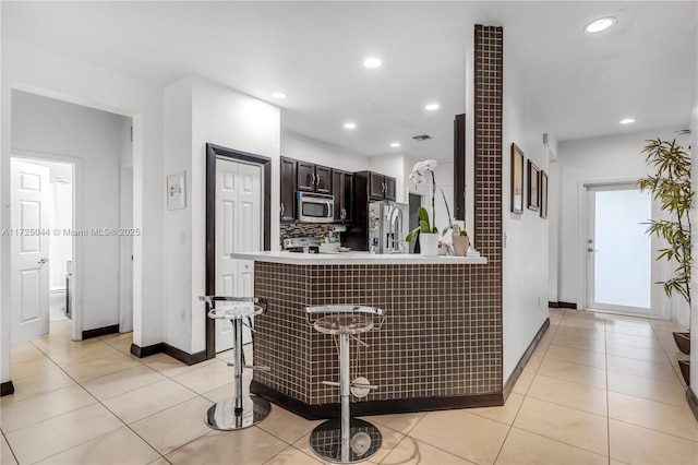 kitchen featuring a kitchen breakfast bar, light countertops, light tile patterned floors, and stainless steel appliances