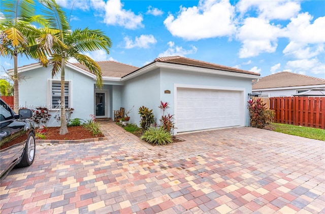 view of front of home with driveway, an attached garage, fence, and stucco siding