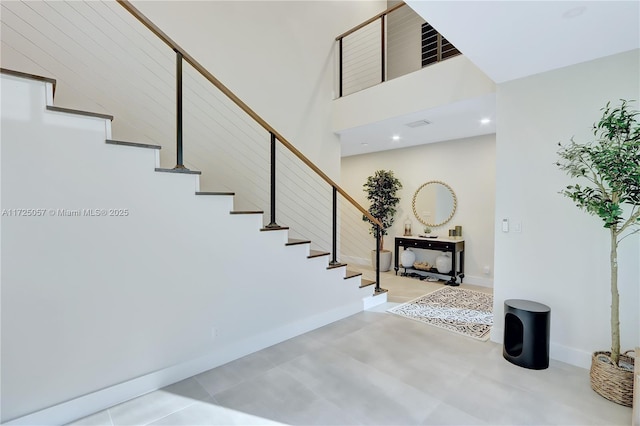 stairs featuring a towering ceiling and baseboards