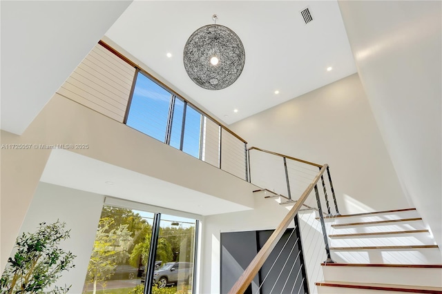 stairway featuring recessed lighting, visible vents, and a towering ceiling