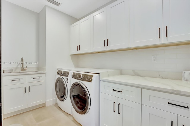 laundry area featuring light tile patterned floors, a sink, visible vents, cabinet space, and washing machine and clothes dryer