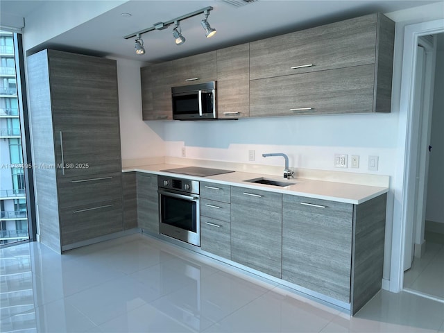 kitchen with sink, light tile patterned floors, stainless steel appliances, and track lighting