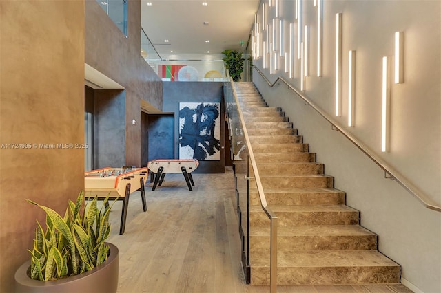 stairs with hardwood / wood-style floors and a towering ceiling