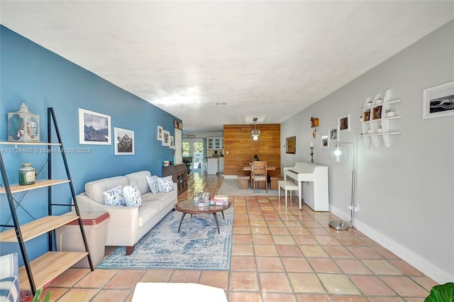 living room featuring tile patterned floors and wood walls