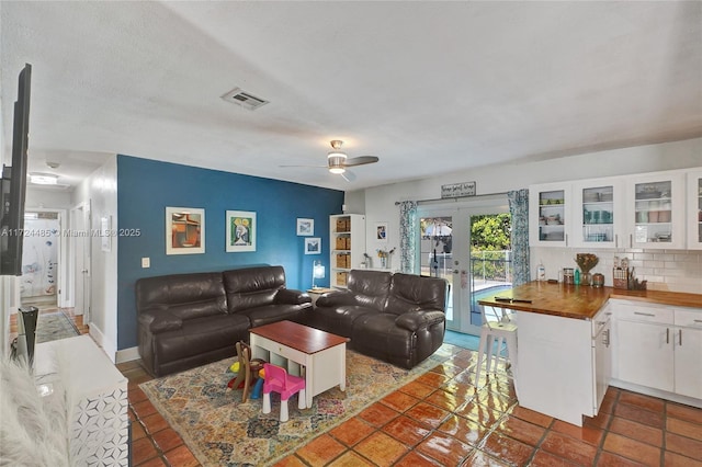 living room featuring dark tile patterned flooring, ceiling fan, and french doors