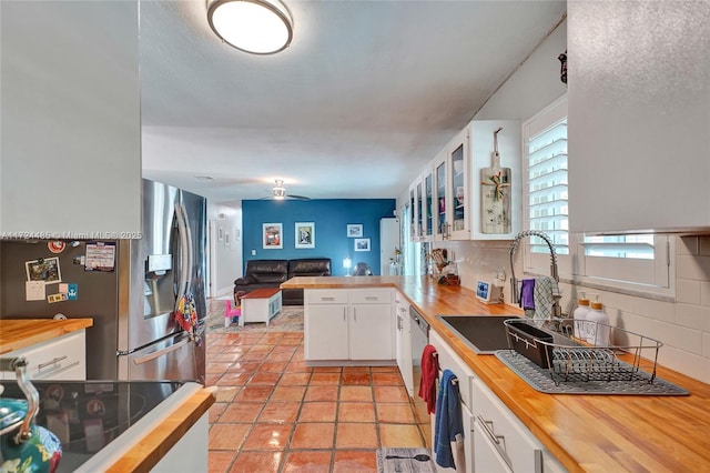 kitchen featuring kitchen peninsula, decorative backsplash, stainless steel appliances, and white cabinetry