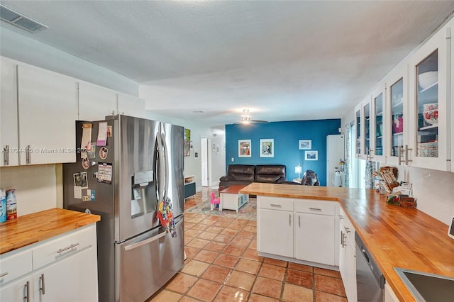 kitchen with ceiling fan, wood counters, decorative backsplash, white cabinets, and appliances with stainless steel finishes