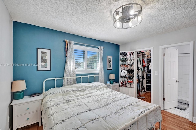 bedroom with a textured ceiling, light wood-type flooring, a spacious closet, and a closet