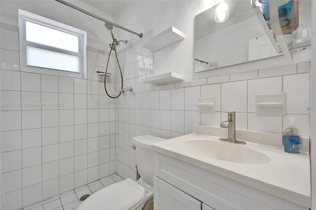 bathroom with vanity, decorative backsplash, toilet, tiled shower, and tile walls