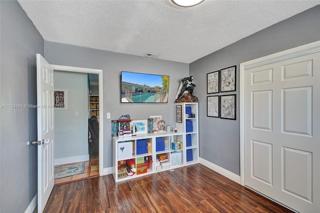 rec room featuring a textured ceiling and dark hardwood / wood-style floors