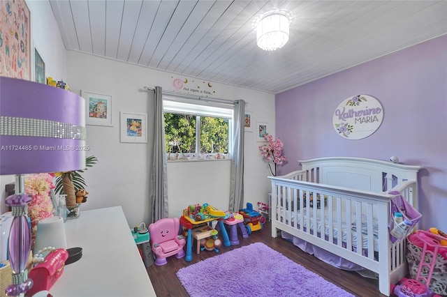 bedroom featuring dark hardwood / wood-style flooring and a nursery area