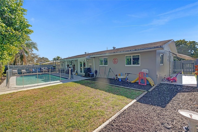 rear view of house featuring a yard, a fenced in pool, and a patio area