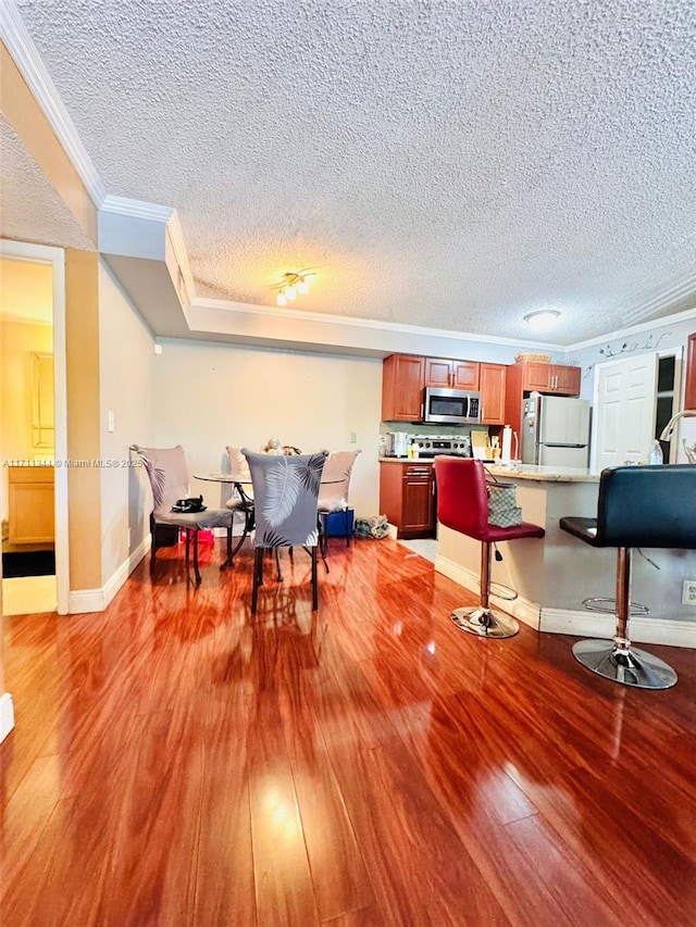 dining space with hardwood / wood-style floors, a textured ceiling, and ornamental molding