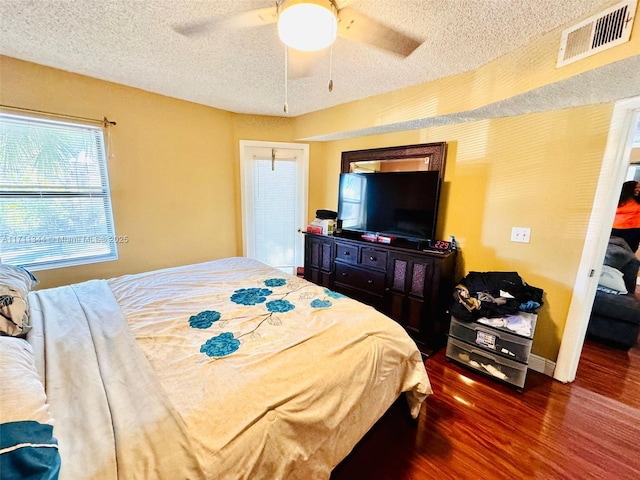 bedroom with ceiling fan, dark hardwood / wood-style floors, a textured ceiling, and a closet