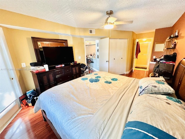 bedroom with ceiling fan, a closet, a textured ceiling, and hardwood / wood-style flooring