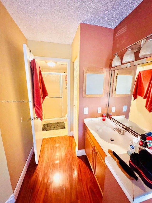 bathroom with a shower with door, vanity, a textured ceiling, and hardwood / wood-style flooring